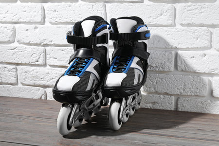 Pair of roller skates on wooden table near white brick wall