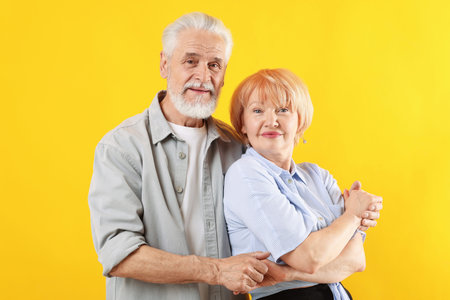 Lovely senior couple together on yellow backgroundの写真素材