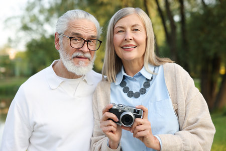 Lovely senior couple with vintage photo camera in parkの写真素材