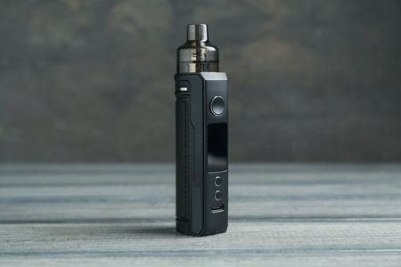 One electronic smoking device on wooden table against gray background, closeup