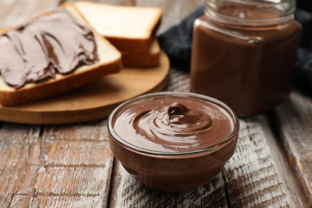 Tasty chocolate butter and slices of bread on wooden table, closeupの写真素材