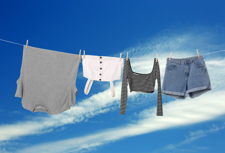 Different clothes drying on washing line against blue skyの写真素材