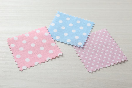 Samples of different fabrics on white wooden table, closeup