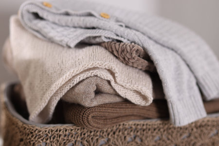 Wool sweaters in basket on light background, closeup