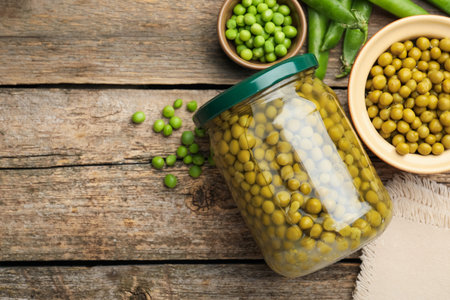 Pickled peas in jar and pods on wooden table, flat lay. Space for textの写真素材