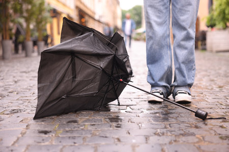 Woman and broken umbrella on wet pavement outdoors, closeupの写真素材
