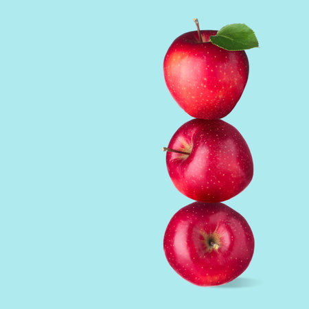 Red apples stacked on top of each other against light blue background. Balanceの写真素材