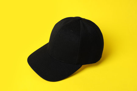 One black baseball hat on yellow backgroundの写真素材