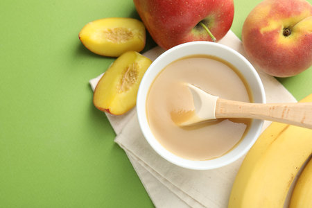 Baby food. Tasty puree in bowl and ingredients on green background, flat lay. Space for textの写真素材