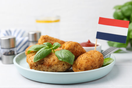 Tasty fried croquettes, basil, sauce and flag of the Netherlands on white tiled table, closeupの写真素材