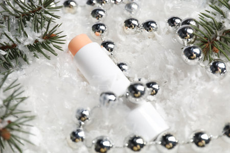 Moisturizing lip balm, Christmas decor and fir tree branches on artificial snow, closeup. Winter careの写真素材
