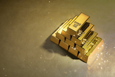 Stacked shiny gold bars on color background. Space for textの写真素材
