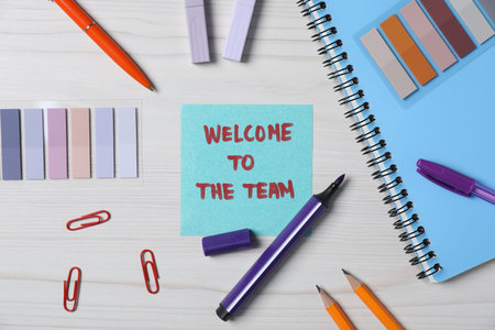 Paper note with phrase Welcome To The Team and stationery on white wooden table, flat layの写真素材