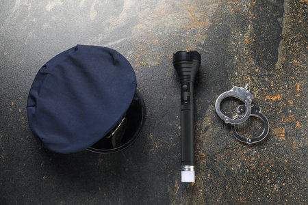 Police cap, flashlight and handcuffs on dark table, flat layの写真素材