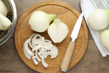 Cut ripe onions and knife on wooden table, flat layの写真素材