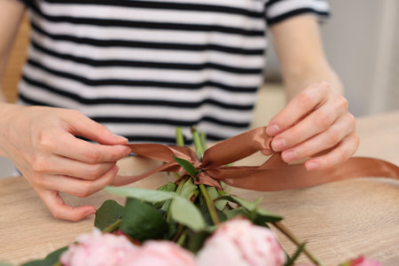 Florist making bouquet of peonies at wooden table in flower shop, closeupの写真素材