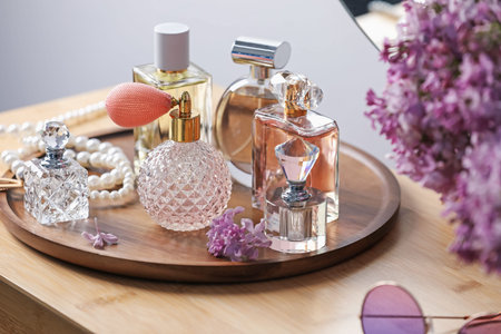 Bottles of perfumes, accessories and lilac flowers on wooden table