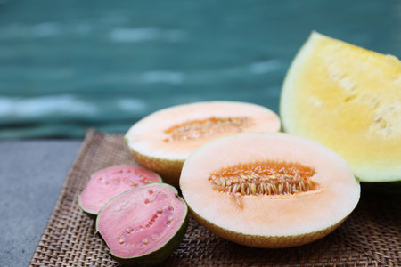 Ripe juicy tropical fruits on wicker tray near swimming pool, closeupの写真素材