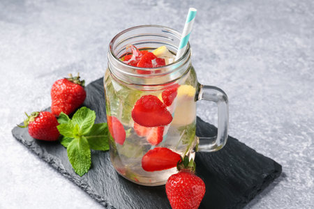 Refreshing drink with strawberries, lemon, ice and mint on gray textured table, closeupの写真素材