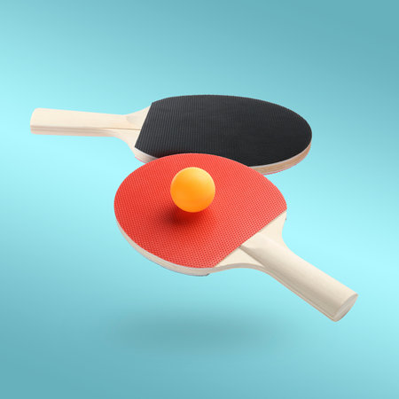 Ping pong rackets and ball in air against light blue backgroundの写真素材