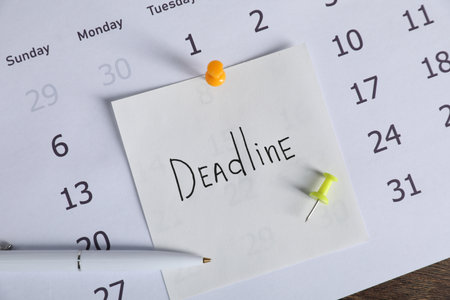 Sticky note with word Deadline, calendar and pen on table, top viewの写真素材
