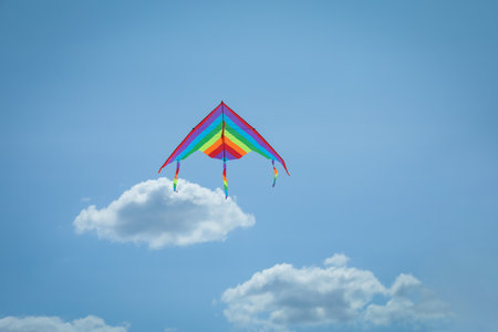 Colorful kite flying in blue sky, low angle viewの写真素材