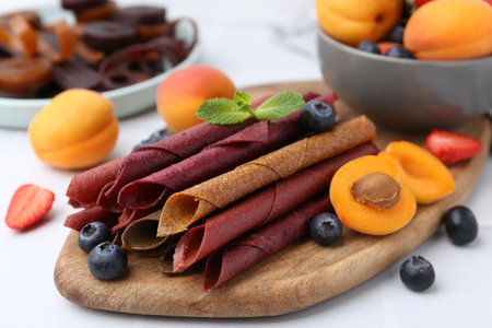 Tasty candied leather rolls, fruits and berries on white table, closeupの写真素材