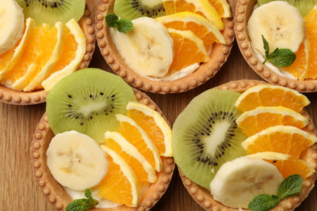 Tartlets with fruits and mint on table, top view. Delicious dessertの写真素材