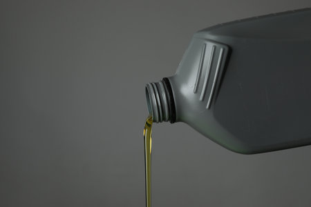 Pouring motor oil from canister on gray background, closeup. Space for textの写真素材