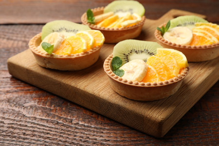 Tartlets with fruits and mint on wooden table, closeup. Delicious dessertの写真素材