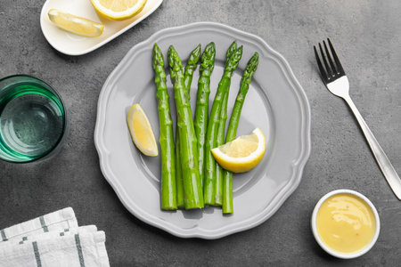 Tasty cooked asparagus served with lemon on gray table, flat layの写真素材