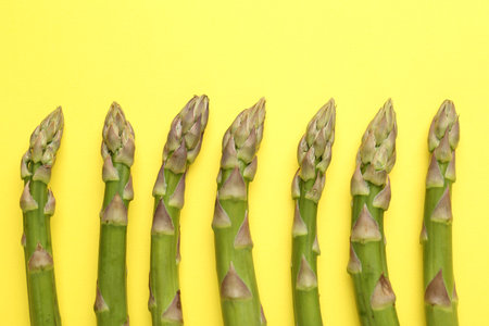 Fresh ripe raw asparagus on yellow background, flat layの写真素材