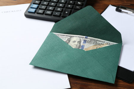 Money bonus. Envelope with dollar banknote, clipboard, checklist and calculator on wooden table, closeupの写真素材