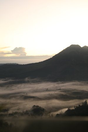 Picturesque view of mountains covered with fog on sunsetの写真素材