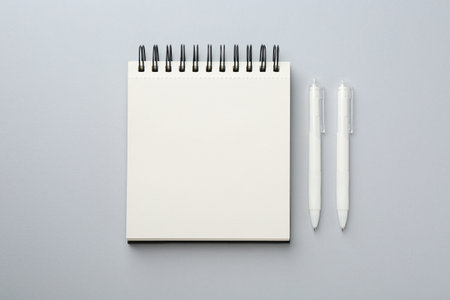 Notebook and pens on gray background, flat lay