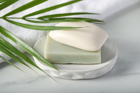 Soap bars, towel and palm leaf on white marble table, closeupの写真素材