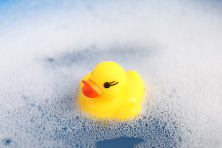 Cute rubber duck floating in water with bubbles, closeupの写真素材