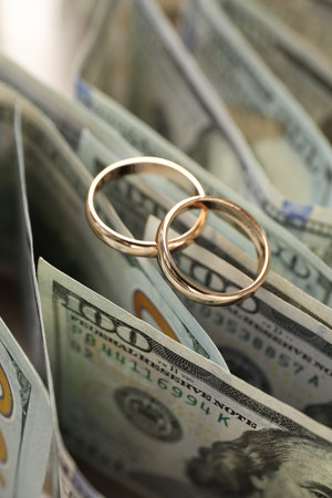 Gold wedding rings and dollar banknotes on table, closeupの写真素材