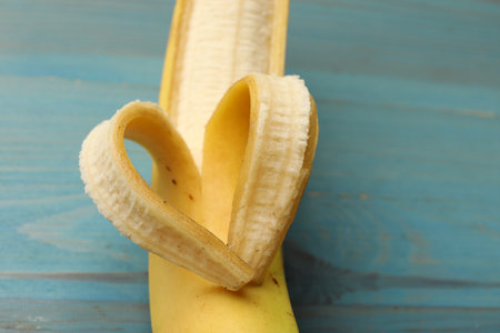 Banana with heart made of peel on light blue wooden table, closeupの写真素材
