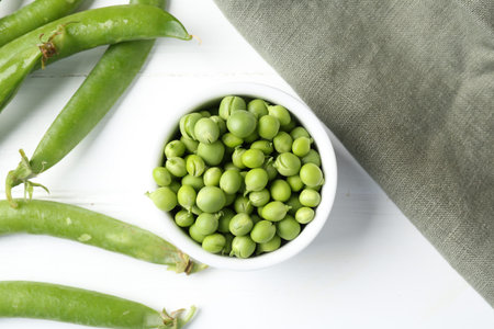 Fresh ripe green peas on white wooden table, flat lay