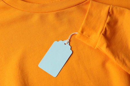 Cardboard tag on orange garment, top viewの写真素材