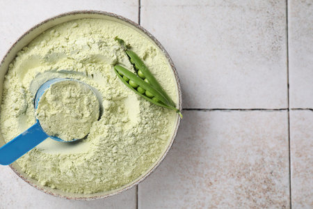 Protein powder and green peas on light tiled table, top view. Space for text