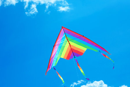 Colorful kite flying in blue sky, bottom view. Space for textの写真素材