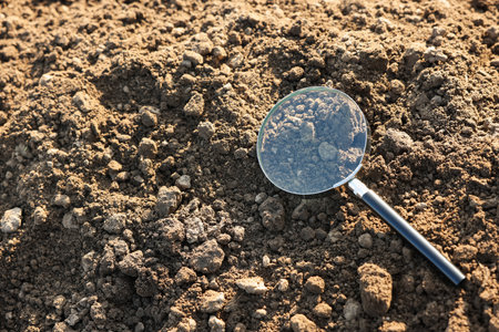 Magnifying glass on dry soil in field, above view. Space for textの写真素材