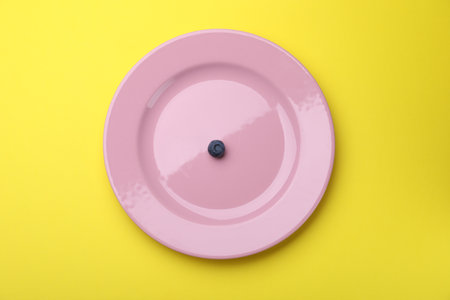 Plate with fresh blueberry on yellow background, top viewの写真素材