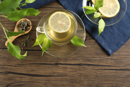 Refreshing green tea with lemon and leaves on wooden table, flat lay. Space for textの写真素材
