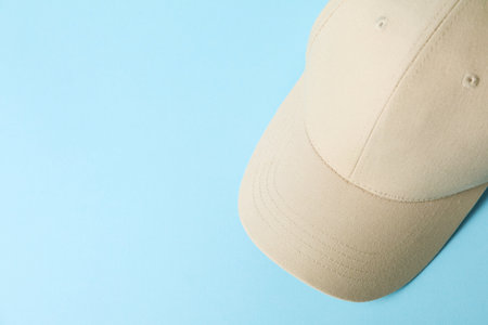 Beige baseball hat on light blue background, top view. Space for textの写真素材