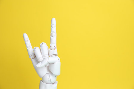 White mannequin hand making rock gesture on yellow background, space for textの写真素材