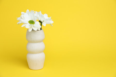 Beautiful white flowers in vase on yellow background, space for textの写真素材