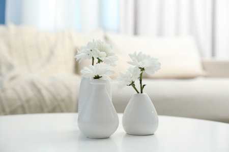 Beautiful chrysanthemum flowers in vases on white table indoorsの写真素材